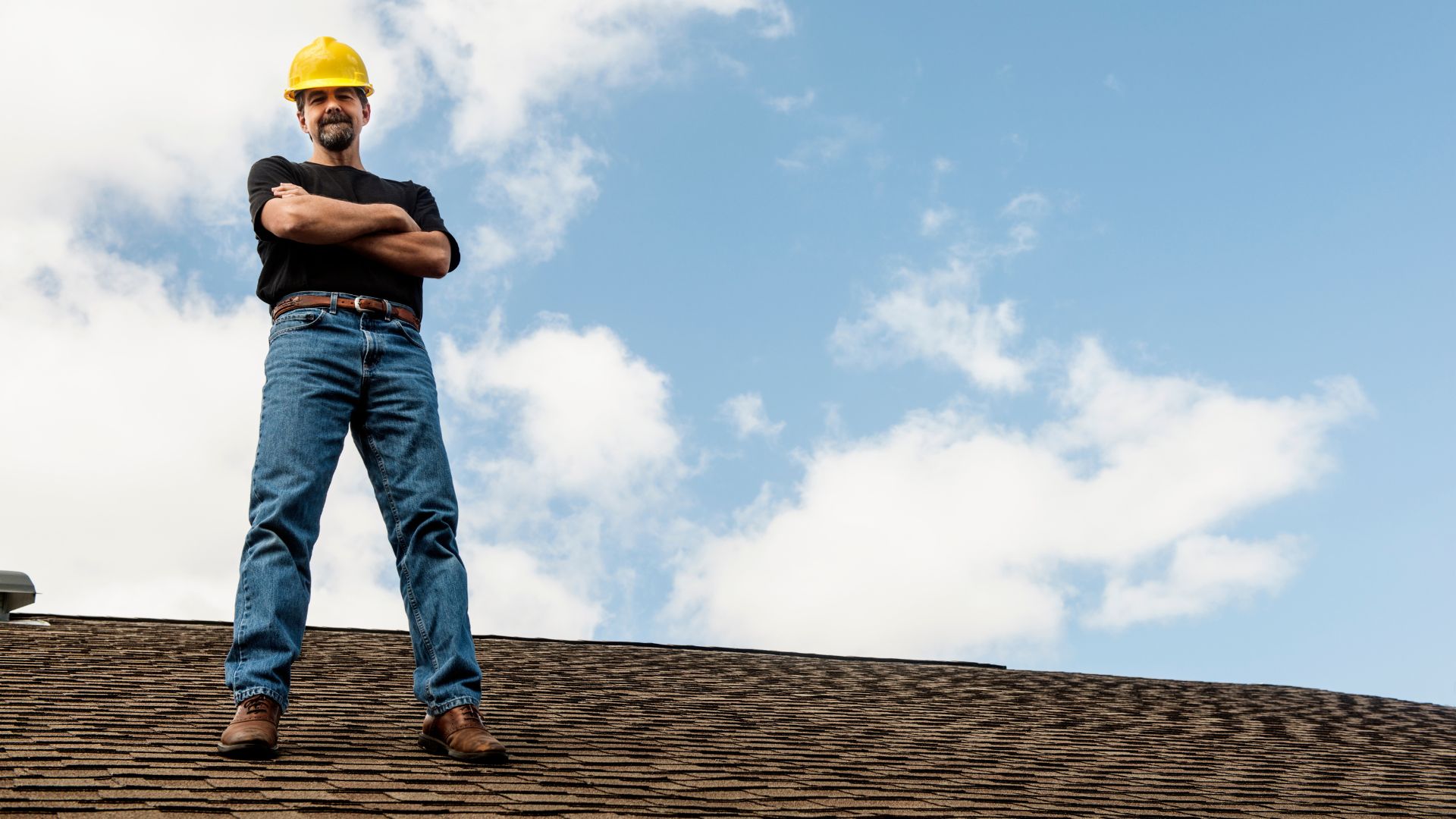A roofer stands on a newly installed roof